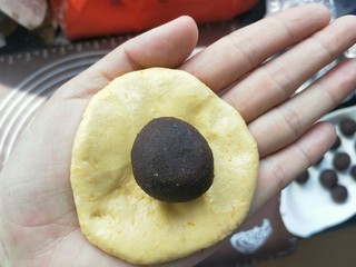 8、南瓜糯米夹心饼,取一块面团按压扁。包入豆沙馅
