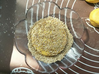 11、南瓜糯米夹心饼,不用擀,用手轻轻按压即可,按压成一个小饼。(不要按压的太扁,我按的有点太扁了,)然后两面都黏上芝麻。做好后可以油炸,可以用电饼铛煎熟。可以烤箱烤。我今天做的无油健康版,烤的。