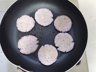 9、紫薯芝麻饼,平底锅放少量油。把紫薯芝麻团按扁在锅里。