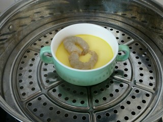 9、虾仁蒸蛋羹,15分钟以后，蛋液已经基本凝固了，打开保鲜膜，把虾仁放在上面，摆成一个心形，盖上保鲜膜，继续蒸五分钟，虾仁熟透即可。