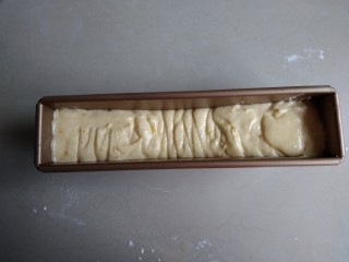 9、柠檬磅蛋糕,将蛋糕糊挤入到长条磅蛋糕模具中，两边高中间低，在桌面上震几下
