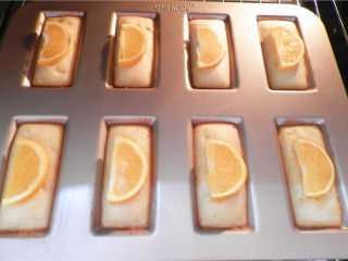 15、橙香费南雪,烤7分钟后，将橙子片分别码在：每个“金砖”的中间。该模具导热性很好， 再烤7分钟左右表面金黄即可。