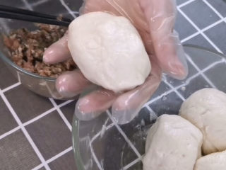 12、梅干菜烧饼,接下来就是做包子一样的步骤了,取一个醒发的面团,用手压平成饼状,再包入梅干菜肉馅,抱起来就好了