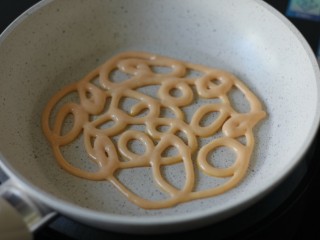 10、网红胡萝卜奶香网格蛋饼,将面糊连贯的挤在平底锅中，花纹随意，但尽量不要有断掉的地方。