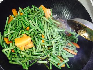 2、豆角焖面,油锅五成热放豆瓣酱翻炒，加入豆角胡萝卜，继续翻炒