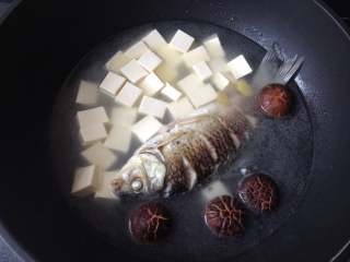 7、鲫鱼豆腐汤,倒入半锅开水，放入豆腐和花菇，加盖焖煮20分钟