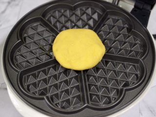 12、南瓜酸奶华夫饼,华夫饼机提前预热后，刷上薄薄的一层黄油，把摁扁的面饼放入机器里，盖上盖子开始烙制。