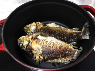 6、奶白鲫鱼豆腐汤,鱼煎好后移到预热好的铸铁锅或者砂锅里;