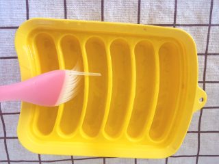 8、宝宝辅食10M➕：奶酪鸡肉肠,将做好的鸡肉泥用勺子倒入裱花袋，在裱花袋的前端剪口，在模具里轻轻刷一层食用油（没有模具的可以用锡箔纸代替）