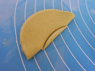 8、????豌豆荚小馒头????,然后将面团对折,在肚子的地方用模具按出一个小半圆形,这个半圆宜小不宜大,因为如果太大的话,后面二发的时候豆子会掉出来喔!这样就会影响造型了。