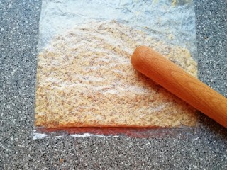 2、芝麻核桃一口酥,核桃仁装进保鲜袋,用擀面杖压碎。