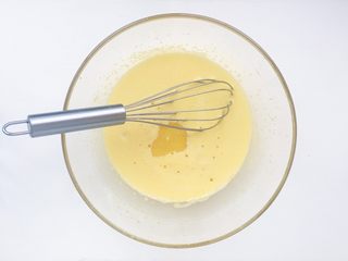 3、电饭煲蒸蛋糕,依次加入牛奶和色拉油搅拌混合均匀备用