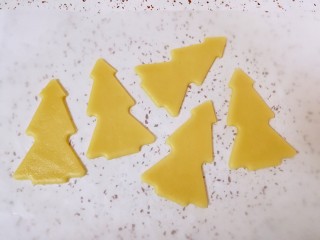 8、圣诞树饼干,去掉边角料，油纸上就只剩下饼干了，和油纸一起移至烤盘上。烤箱上下管160度预热。