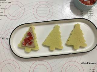 11、迷你圣诞树蛋糕,取一片蛋糕片，挤上奶油，放上草莓，再挤上一层奶油，盖上另一片蛋糕片。