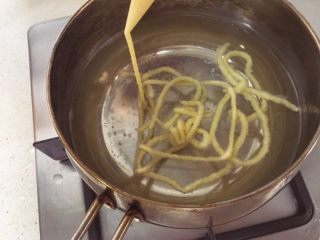 9、宝宝辅食9M➕:青菜鳕鱼面线,锅里加入适当水,水煮沸后转小火,开始在锅里转圈圈挤面线,面线挤完后再继续小火煮两分钟