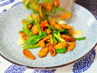 10、韭香蚕蛹,最后淋入几滴香油,翻炒几下,就可以装盘了。