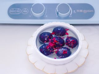 14、星空水晶奶黄汤圆,做好的星空水晶奶黄汤圆出锅咯,捞出后盛到碗里,撒上玫瑰花碎就可以食用咯。