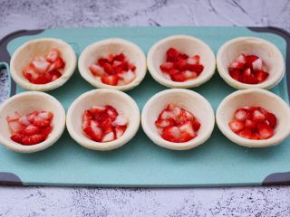 4、草莓芝士酥～蛋挞皮版,看见蛋挞皮软化以后，把切丁的草莓均匀的放到蛋挞皮里。