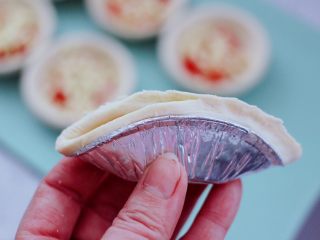 6、草莓芝士酥～蛋挞皮版,把蛋挞皮对折一下，然后从蛋挞的一边开始捏起。