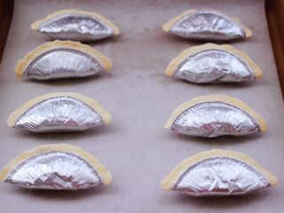 8、草莓芝士酥～蛋挞皮版,依次做完所有的蛋挞皮，烤盘上铺一张油纸，把做好的草莓芝士酥，放入烤盘中。