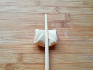 19、紫薯馅老婆饼, 取一个松弛好的卷，用筷子从中间压一下，让两头翘起。