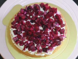 11、金秋蛋糕,火龙果切成小块，蛋糕块上先抹上一层淡奶油，再撒上一层火龙果，用抹刀整理、稍微抹平，每一层都依次做好，将蛋糕块小心摞起来。