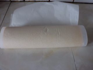 18、草莓香草奶油蛋糕卷,用擀面杖辅助卷成e形卷，擀面杖放在油纸下面，一边用擀面杖提起油纸双手手指压住蛋糕片顶端卷到一半，刚好包住所有的草莓，左手扶住蛋糕片底端，右手提起油纸，快速的把蛋糕片卷到底部，擀面杖必须贴住桌子，左手向前拉扯油纸，擀面杖卷紧蛋糕卷向身体方向拉，让蛋糕卷在油纸的辅助下成形卷成一个圆，蛋糕片收口在下方^o^