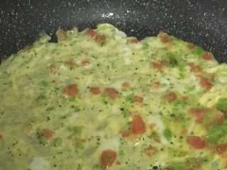 6、宝宝辅食之番茄芝士厚蛋烧,热锅刷油，开小火，倒入一半的蛋液，左右晃动煎锅，可以使蛋液铺的更平整。
