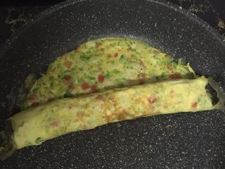 7、宝宝辅食之番茄芝士厚蛋烧,待底部凝固后马上卷起。