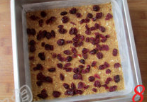 8、椰香坚果乳酪条,模具里边铺上油纸,把混匀的饼干底材料倒入,用手压实压平,再撒上蔓越梅干。