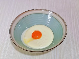 4、半熟芝士蛋糕,将器具从热水中取出，先加入一个蛋黄，搅拌均匀后再加一个搅拌均匀，再加入第三搅拌均匀。(每次一定要搅拌均匀后再加入下一个蛋黄)