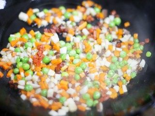 7、色彩缤纷的菠萝炒饭,倒入胡萝卜、豌豆和香菇翻炒片刻。