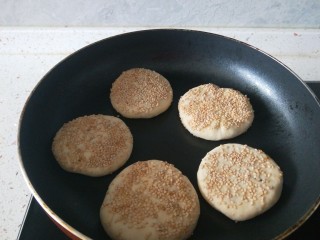 12、糖火烧,饼披刷上水沾上芝麻冷锅放入锅中。