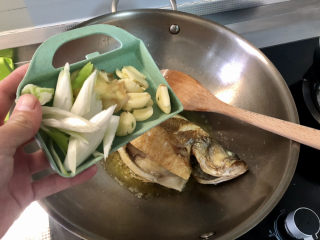 13、红烧鱼,鱼推到一边,放入葱白姜片蒜瓣,小火煸香