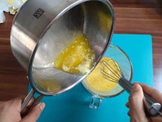 2、柠檬草莓蛋糕,把融合的黄油,缓缓倒入蛋黄柠檬汁混合液中,一边倒,一边用蛋抽搅拌,然后把混合好的液体倒回小锅,继续小火加热,边加热,边搅拌