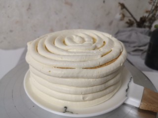 11、柠檬草莓蛋糕,继续再制作外层柠檬奶油,外层柠檬乳霜把除了柠檬乳外的其他原料一起打发,打到奶油浓稠再一次加入剩余的柠檬凝乳,再打到有纹路,不流动即可。装到裱花袋里,剪一个一厘米宽口,如图抹一圈