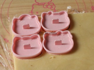 9、kitty奶酪饼干,取出面团，剪开表面的保鲜膜，把学厨Kitty的饼干压模先压出外形轮毂，把五官的压模在面粉里粘一下再压出Kitty一家的五官（萌萌哒）然后抽掉模具