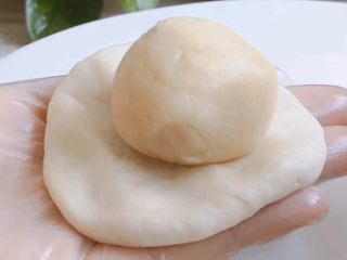 4、酥皮豆沙月饼,取一个水油皮,按压包入一个油酥,捏紧收口
