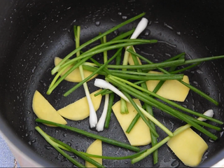 4、电饭煲盐焗鸡—一滴水都不加，做出来的鸡却嫩滑多汁,电饭煲内胆刷层底油，放入葱段、姜片。
