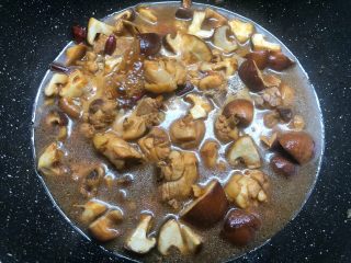 7、黄焖鸡,再倒入200毫升水,加入香菇块翻炒均匀,盖上锅盖焖15分钟。