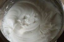 5、草莓奶油蛋糕卷卷,加入剩余细砂糖，将蛋白打至干性发泡，提起打蛋器呈锯齿状