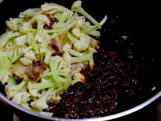 7、干锅菜花,菜花刚刚开始变色时，把它推到锅子一边，放入豆瓣酱小火炒出红油。利用锅底的余油就好，不必另外放油。