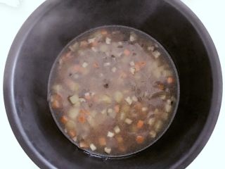 7、宝宝辅食：有饭、有菜、有肉，啥都有的土豆牛肉焖饭！18M+,把浸泡好的大米放入电饭锅，倒入步骤9的所有食材和汤料，并且翻拌均匀，按下电饭锅煮饭模式就可以了。