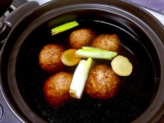 12、红烧狮子头,把丸子放进容量大的砂锅，把姜切片放进去，葱段、蚝油、冰糖、红烧酱油也放进去，添加足够的清水。