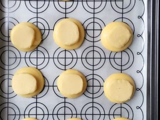 3、西树泡芙,面糊装入裱花袋中,在烤盘有间隔地挤入泡芙,冰箱中酥皮糊取出切片置于泡芙面糊上。