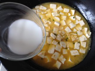 12、金沙豆腐,稍微煮两分钟转小火，撒点白胡椒粉，再慢慢倒入水淀粉，并用锅铲轻推豆腐，使汤汁变得略微粘稠即可