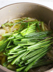 5、葱油酥香干拌面,续加入葱绿段,中小火炸约1分钟后转中大火,