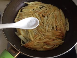 11、土豆丝饼,等下面完全煎好，土豆饼自然成形后，再翻面。往翻过来的一面撒上刚刚多余的盐。