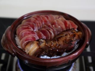 7、煲仔饭,7.煮开后,当饭开始收水,可以看到饭表面有一个个的洞,就将切好的肉片码入。