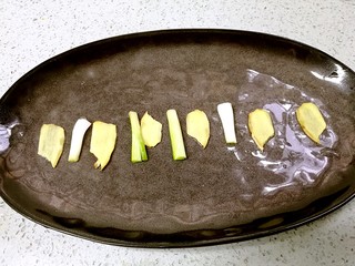 6、粤式清蒸鲈鱼,把姜片和葱段摆放在鱼盘上。